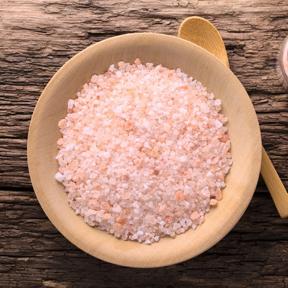 Pink salts in a wooden bowl on a rustic wooden surface. Camel Nuts Singapore