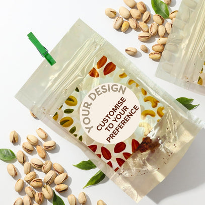 Clear plastic bag with customizable label surrounded by nuts on a white background. Camel Nuts Singapore great idea for full month baby showers.