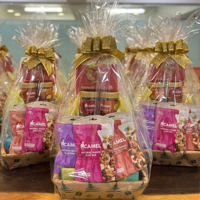 Gift baskets with Camel Nuts products wrapped in clear cellophane with gold ribbons.
