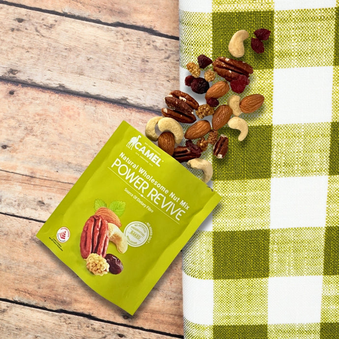 Green package of Camel Nuts Power Revive nut mix on a wooden surface with a checkered cloth background