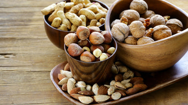 Three wooden bowls filled with various nuts. Camel Nuts Singapore