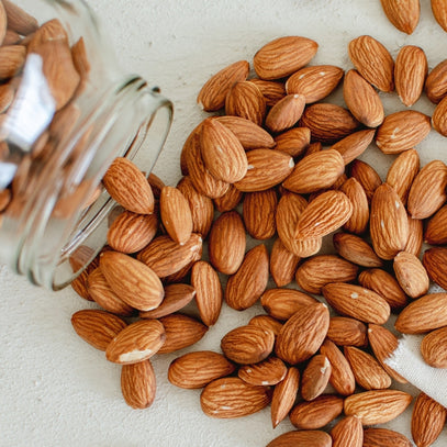 Singapore's Camel Nuts almonds spilling from jar – Almonds poured out of a glass jar.
