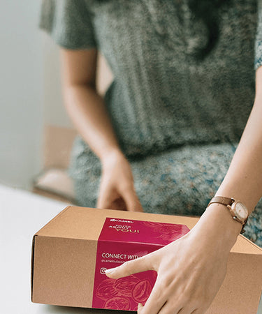 Woman holding a Camel Nuts cardboard box with a red label. Make an impression in corporate events and gifts!