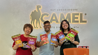 Three Camel Nuts employees, happy, holding bags of Camel Nuts.