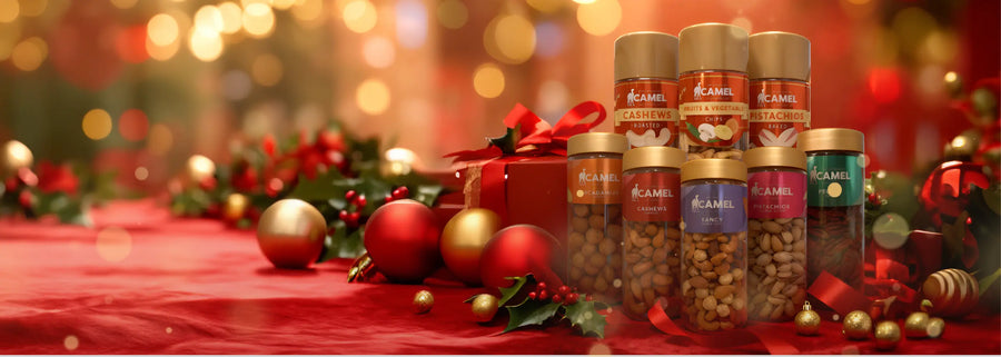 Camel festive gift set featuring assorted nuts in jars, displayed on a red holiday-themed background with ornaments and ribbons.