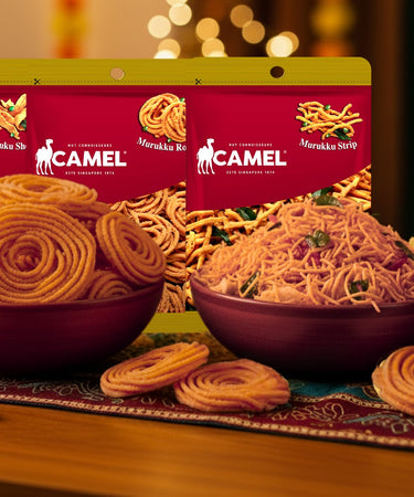 Camel Nuts muruku snack packages on a decorative table with festive lights in the background to celebrate Deepavali