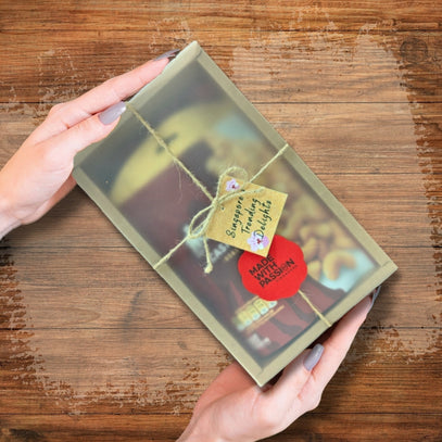 Hand holding a gift box of cashews with a tag. Camel Nuts Singapore