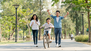 Family of three enjoying a bike ride in a park. Camel Nuts Singapore
