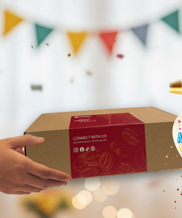 Person holding a Camel Nuts gift box with balloons in the background
