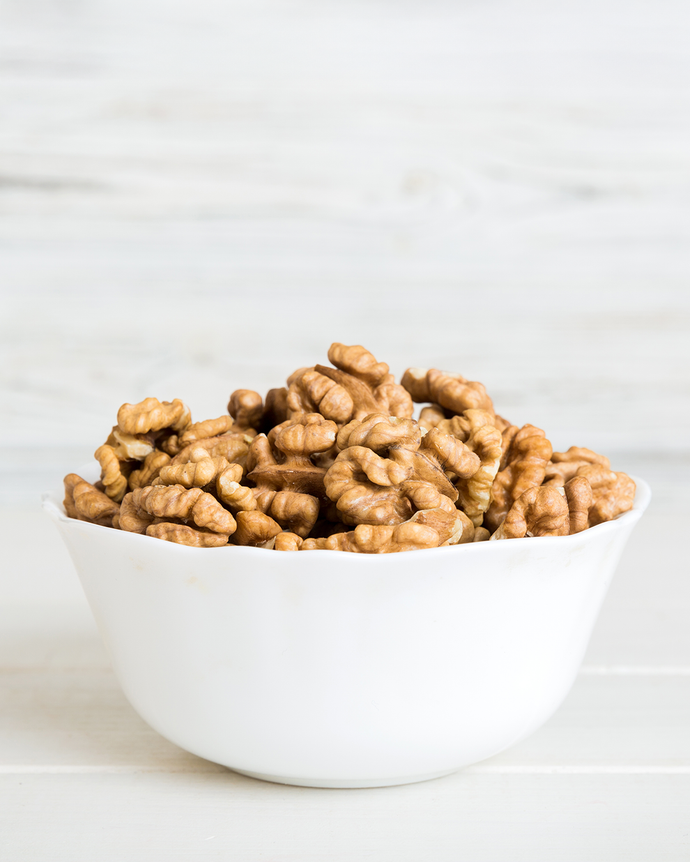 Camel Nuts Singapore walnuts in white bowl – Bowl filled with walnut halves against a light background.