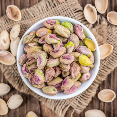 Pistachios in a white bowl on a wooden surface with burlap. Camel Nuts Singapore
