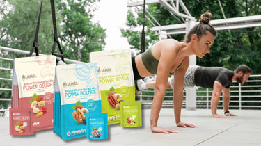 Woman and man doing push-ups outdoors with Camel Nuts Power Series products displayed.