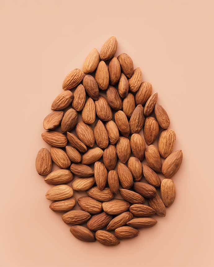 Camel Nuts Singapore almonds arranged in almond shape – Almonds styled in a teardrop pattern on pastel background.