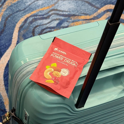 Camel Nuts Power Delight packet on a teal suitcase with a patterned carpet background