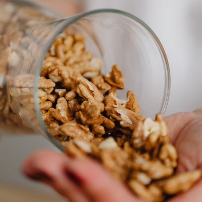 Walnuts being poured – Camel Nuts Singapore walnuts from a glass jar into a hand.