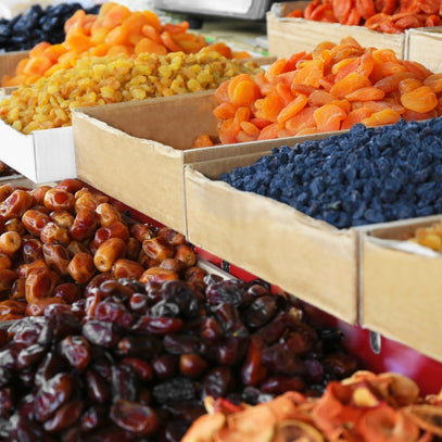 Assorted dried fruits in wooden boxes on a market stall.